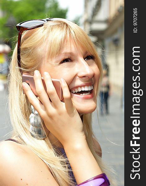 Closeup portrait of beautiful blond woman speaking by phone in city environment. Closeup portrait of beautiful blond woman speaking by phone in city environment.