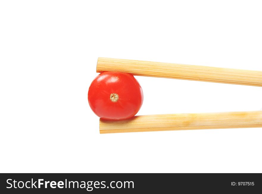 Tomato in chopsticks isolated against white