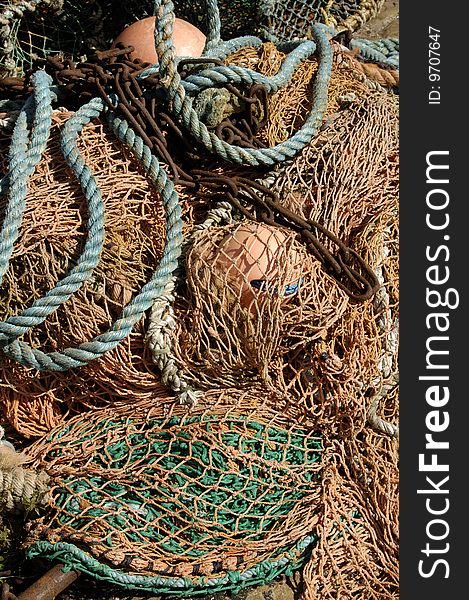 Fishing nets, ropes, chain and buoys lying in sunlight. Fishing nets, ropes, chain and buoys lying in sunlight