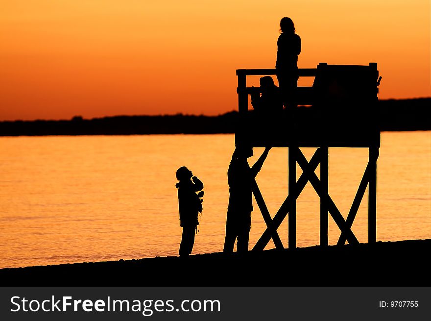 The sun goes down on Hardings Beach at Chatham, Massachusetts, creating a golden backdrop to the silouetted figures and lifeguard chair. The sun goes down on Hardings Beach at Chatham, Massachusetts, creating a golden backdrop to the silouetted figures and lifeguard chair.