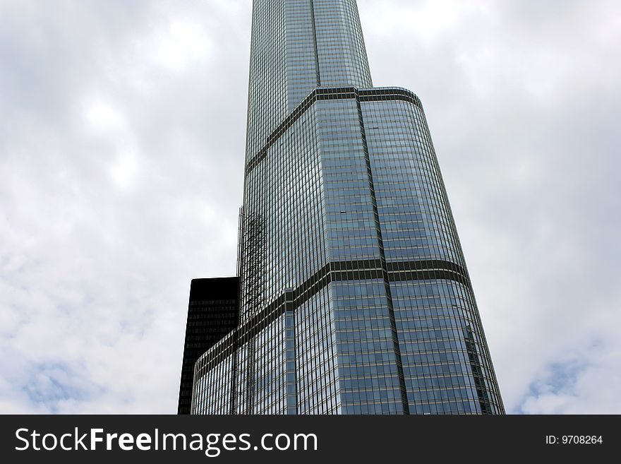 A closeup of a modern skyscraper with the cloudy sky as a background