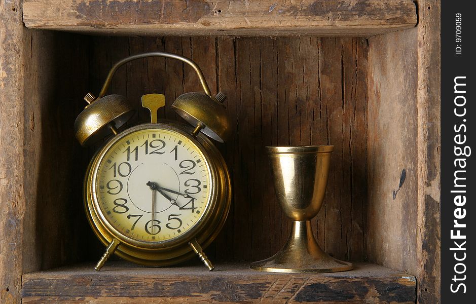 Old dusty alarm clock on a wooden shelf