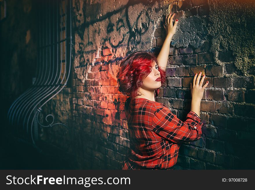 Woman in Red Black and White Plaid Holding Gray Concrete Wall