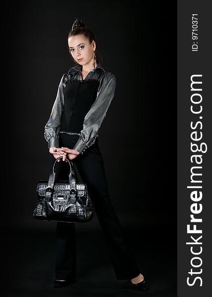 Fashion model with bag posing in dark studio. Fashion model with bag posing in dark studio