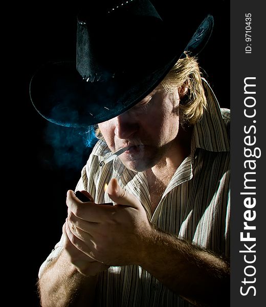 Man In Cowboy Hat Lights A Cigarette