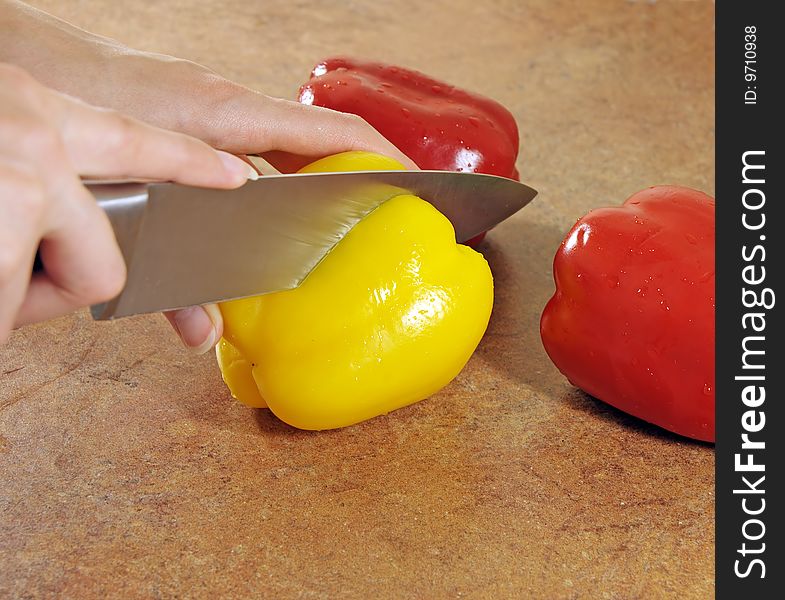 Female hands start to cut multi-coloured pepper. Female hands start to cut multi-coloured pepper