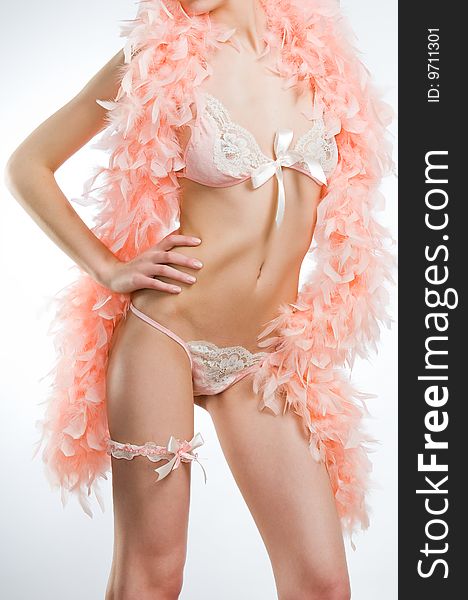 Attractive young woman in pink lingerie with feather boa, studio shot