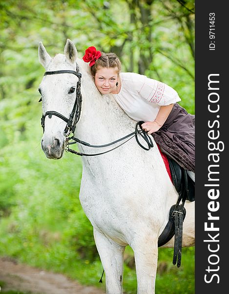 Beautiful girl riding white horse in the forest