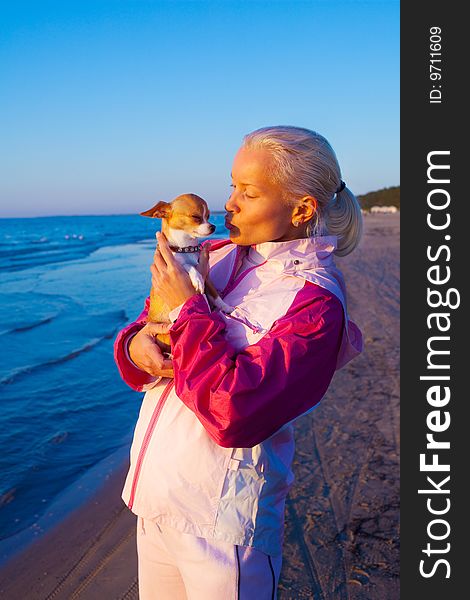 Young woman kissing her dog on a beach. Young woman kissing her dog on a beach