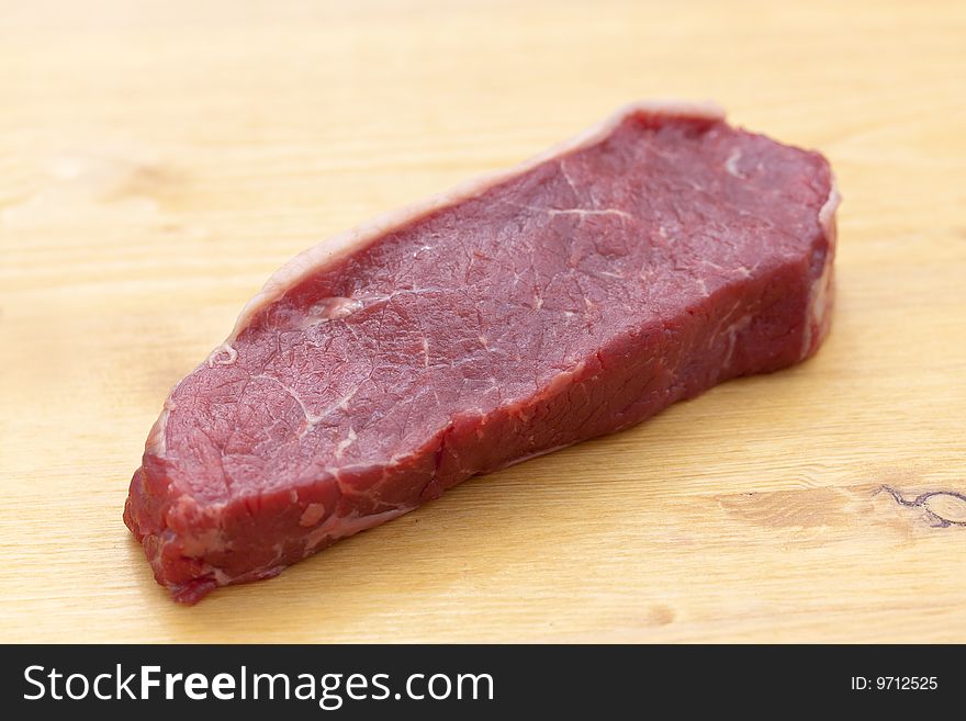 Uncooked Steaks On Wooden Cutting Board