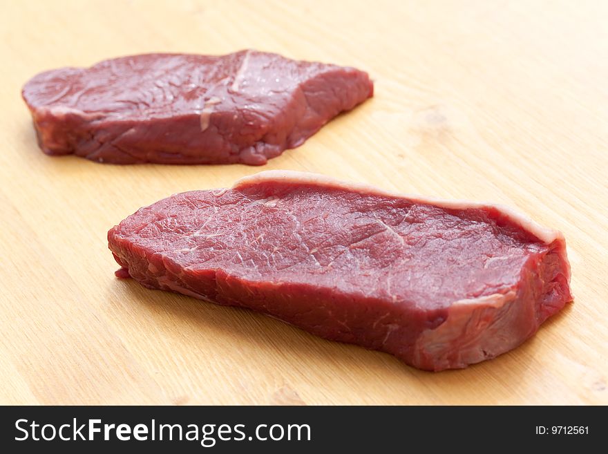 Uncooked Steaks On Wooden Cutting Board