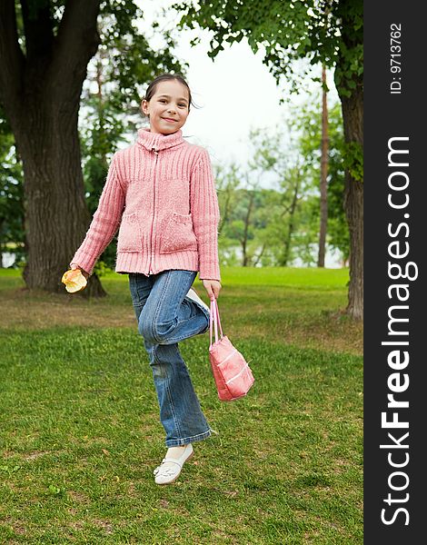 Girl jumps on a green grass against trees
