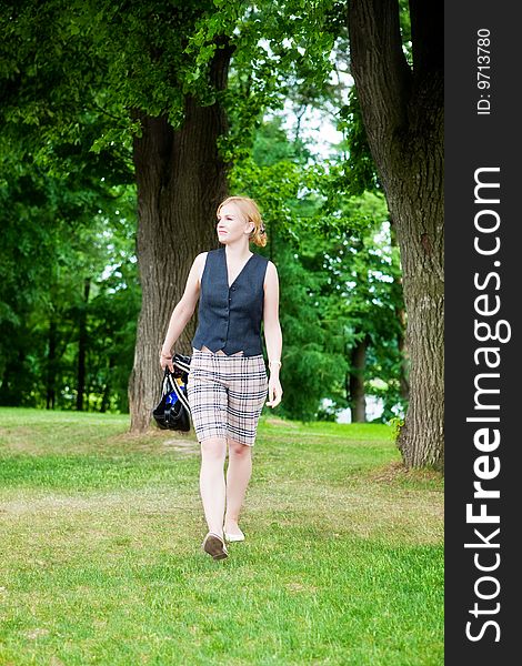Beautiful woman walks on a green grass in park