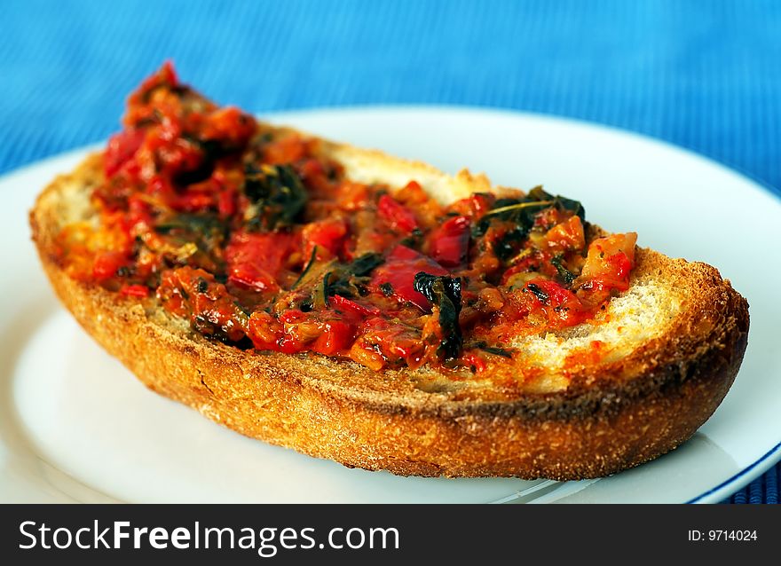Toast with grilled tomato and herbs, white plate and blue background, shallow DOF
