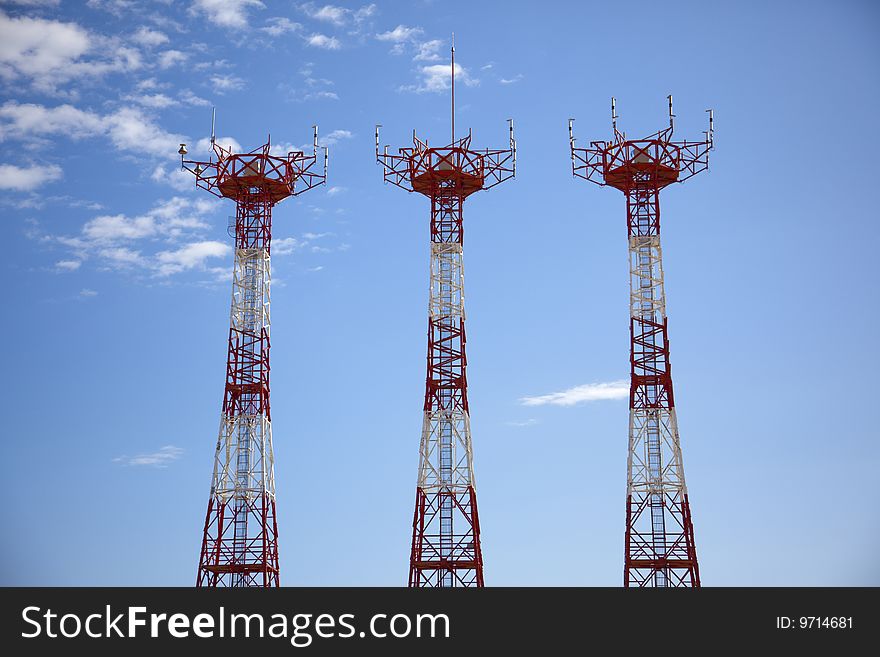 Three antennas with sky and clouds in the background