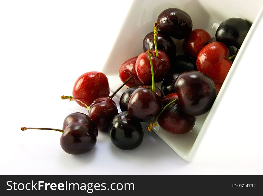 Spilt bowl of cherries with white background with clipping path