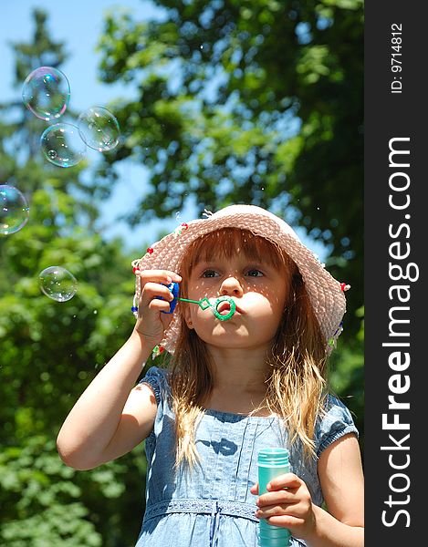 Adorable little girl playing with a bubble wand. Vertical.