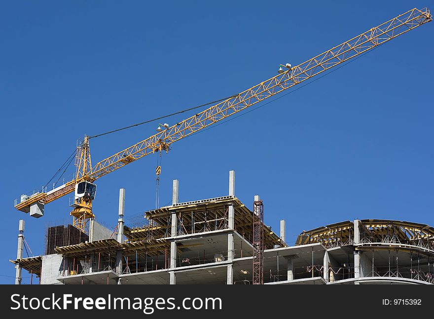 Crane on construction site and blue sky in background. Crane on construction site and blue sky in background.