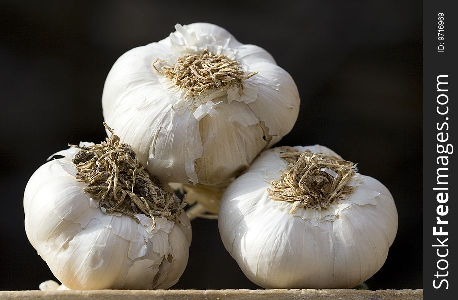 Close up of three garlic on a dark background
