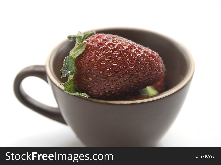 Brown coffee cup full of strawberries on a white background. Brown coffee cup full of strawberries on a white background