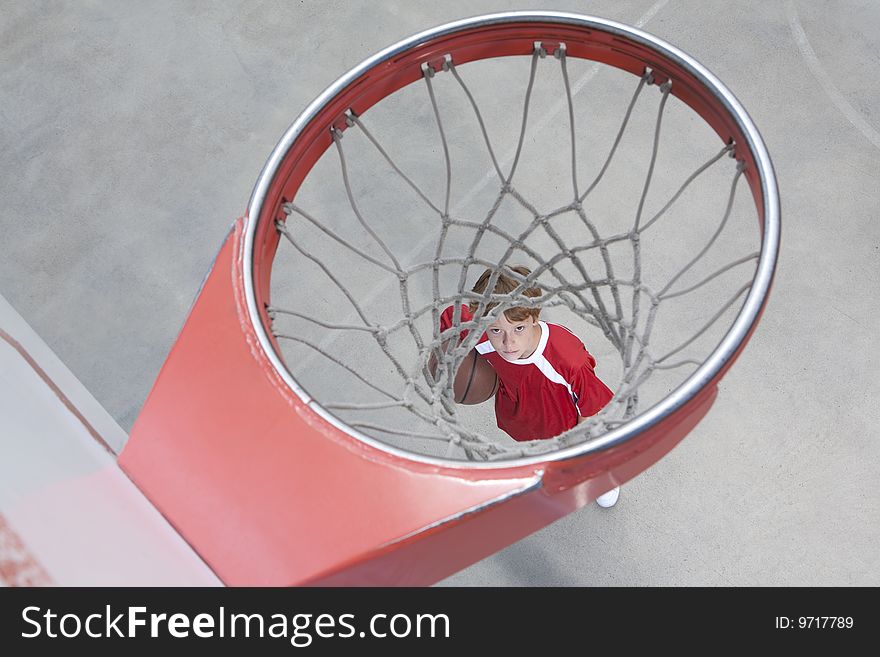 Boy standing looking up through basketball hoop. Boy standing looking up through basketball hoop