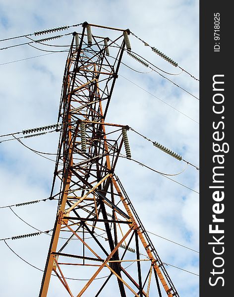 An electrical tower with clouds and sky in the background.