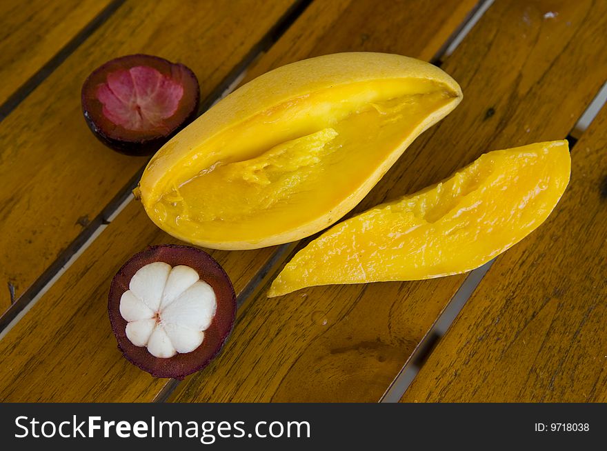 Cut tropical fruits on a wooden little table