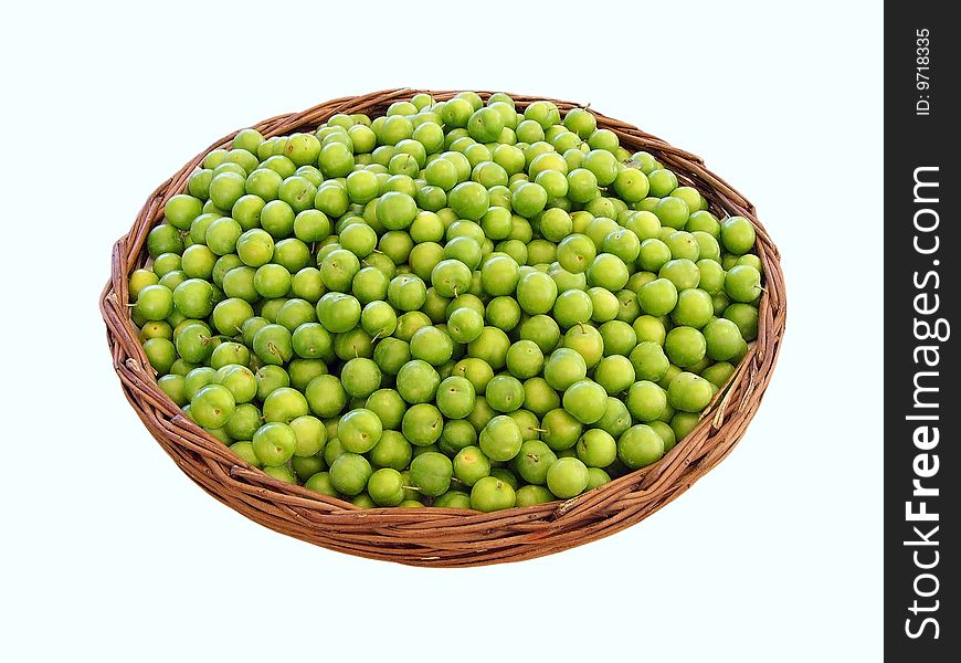 Lots of green plums in a basket, isolated on white background