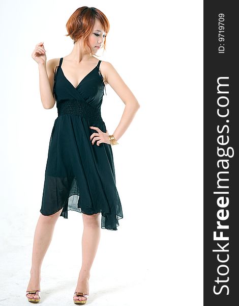 Studio portrait of a beautiful young Asian woman wearing a dress and heels in profile, her face turned toward the viewer.  Isolated on a white background. Studio portrait of a beautiful young Asian woman wearing a dress and heels in profile, her face turned toward the viewer.  Isolated on a white background.