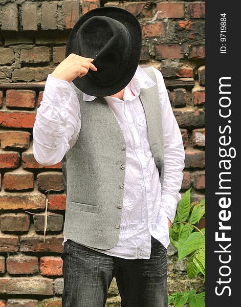 Fashion man with hat posing at the brick wall