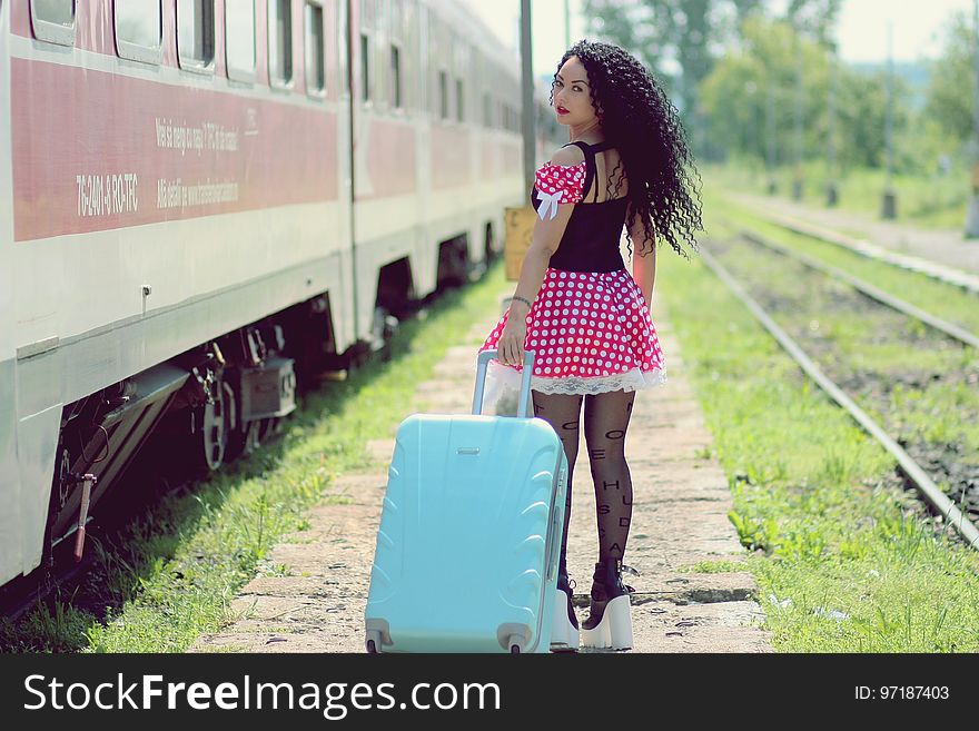 Young Woman With Luggage Standing on Train in City