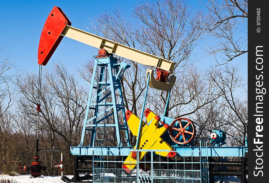 Oil pump at winter with trees at bacground