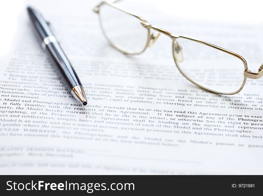 Close-up of document, eyeglasses and pen.