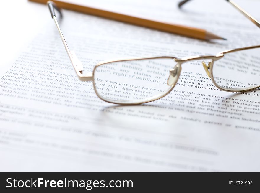 Close-up of document, eyeglasses and pencil.