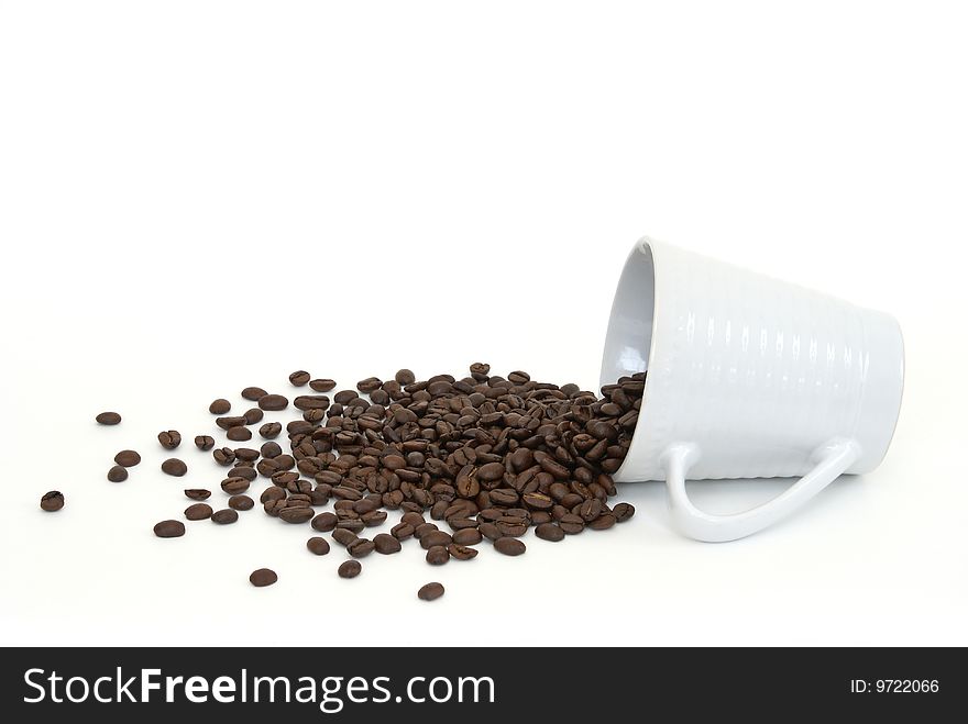 A cup of coffee beans has spilled onto a white background. A cup of coffee beans has spilled onto a white background.