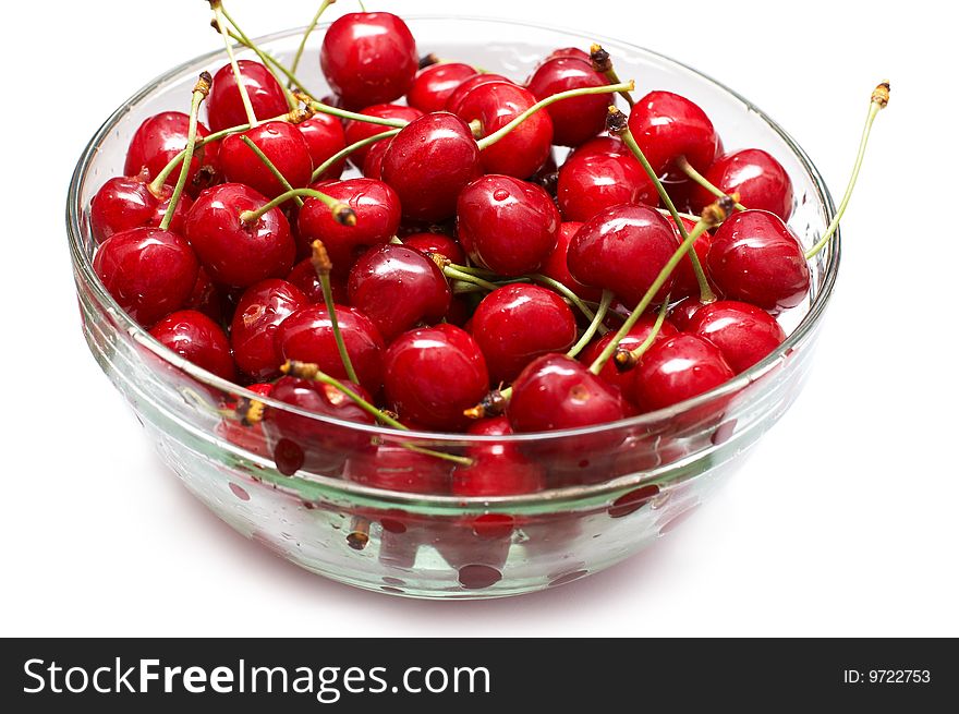 Red-ripe cherry in glass bowl on white background