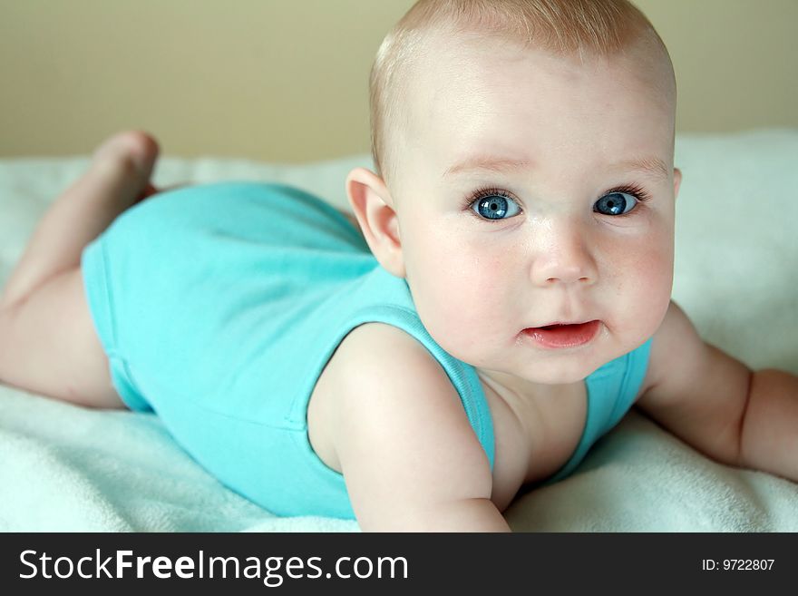 Portrait of sweet baby. Seven months old baby boy lying on blue blanket.