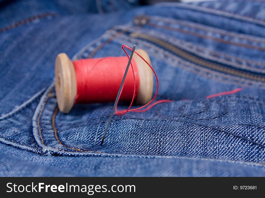 Needle with read thread on jeans.