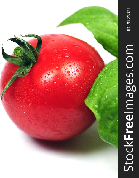 A ripe tomato and some fresh basil leaves. A ripe tomato and some fresh basil leaves