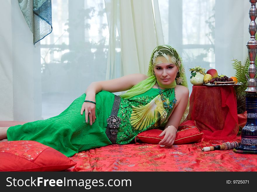 Portrait of beautiful east tsarina, on a carpet with a hookah and fruit. Portrait of beautiful east tsarina, on a carpet with a hookah and fruit