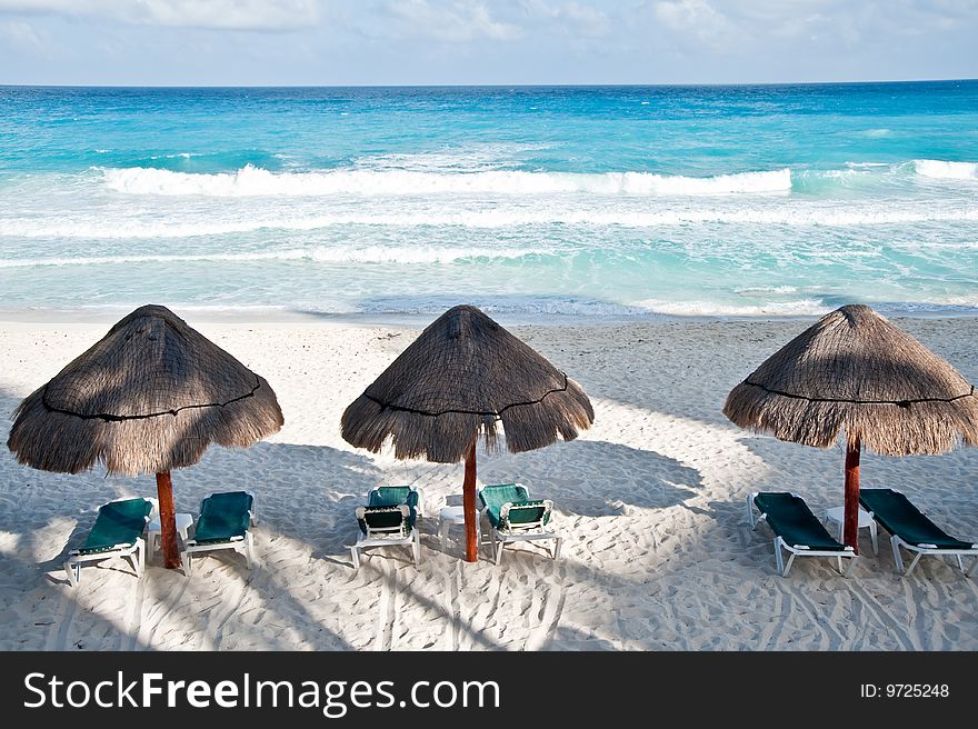 Three straw sun umbrellas by the beach