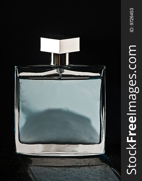 A bottle of perfume isolated on a black background with a reflection on black granite.