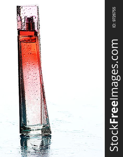 A wet perfume bottle with an elegant shape isolated on white.