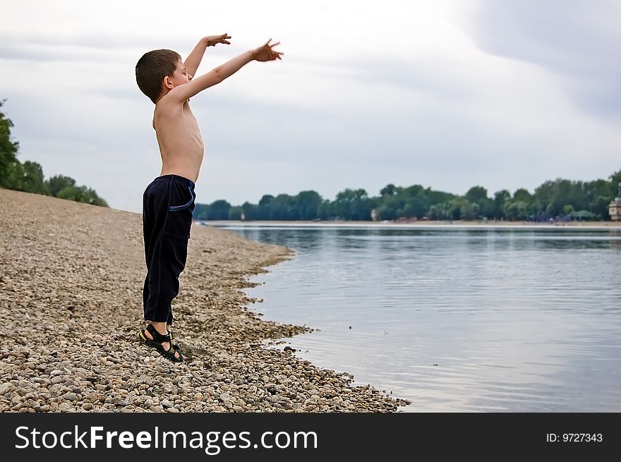 Little kid jumping next to coast of big lake. Little kid jumping next to coast of big lake