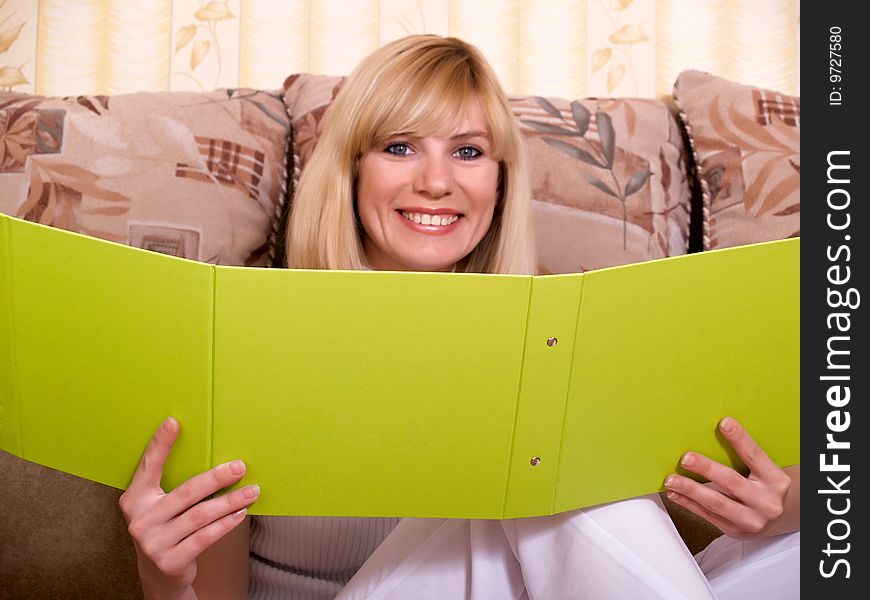 The beautiful girl sits at home with a folder for documents. The beautiful girl sits at home with a folder for documents