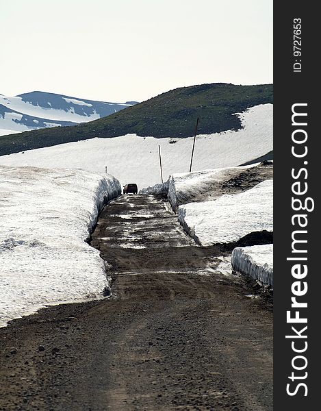 Car goes through enormous snow on background of the mountains