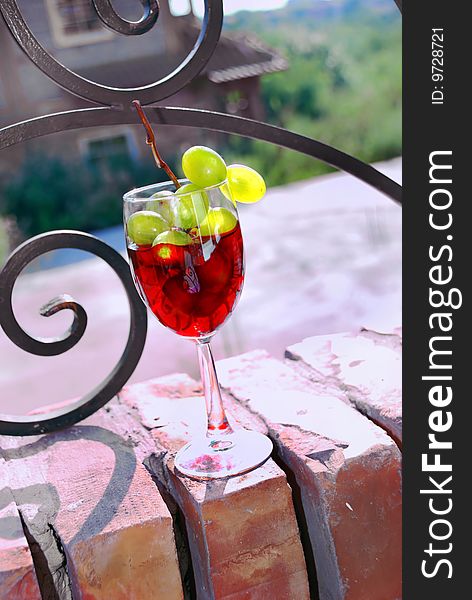 Red wine glass with grape over brick fence. Red wine glass with grape over brick fence