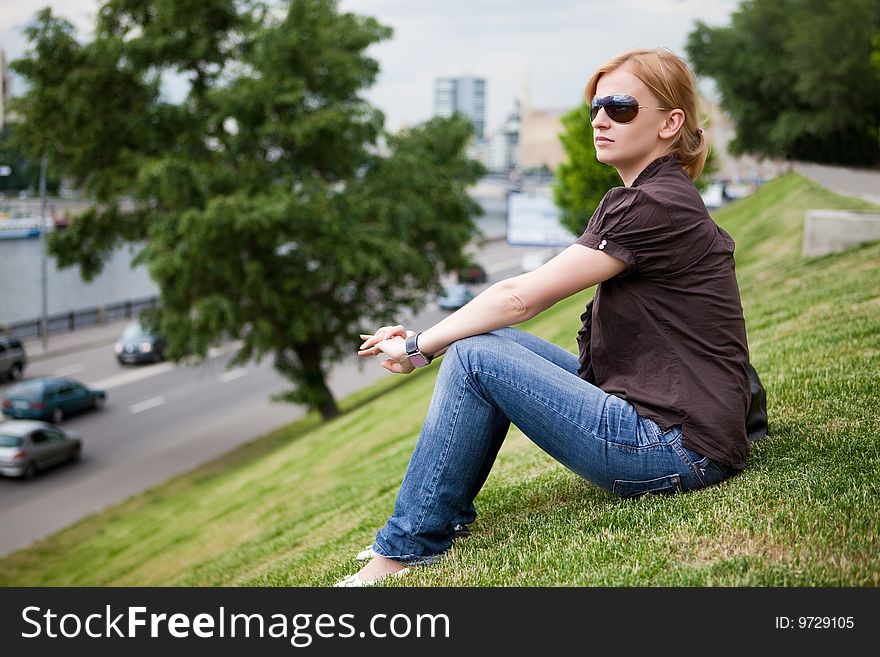 Beautiful girl sits on a hillock at road. Beautiful girl sits on a hillock at road