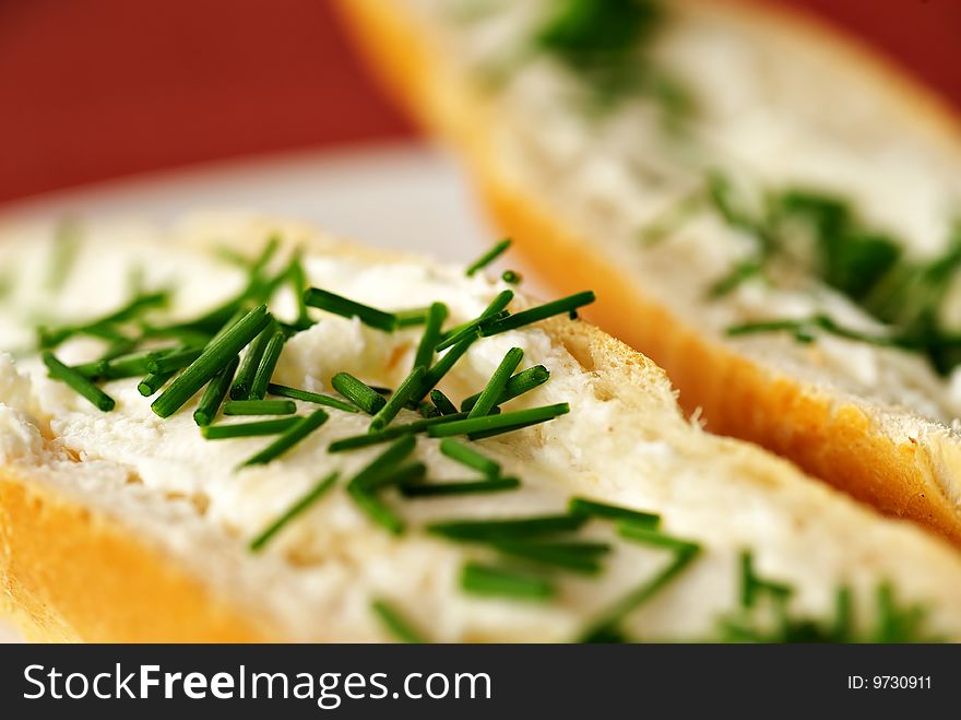Close up detail of bread roll with cheese and chives, shallow DOF, red - purple background, white plate,. Close up detail of bread roll with cheese and chives, shallow DOF, red - purple background, white plate,