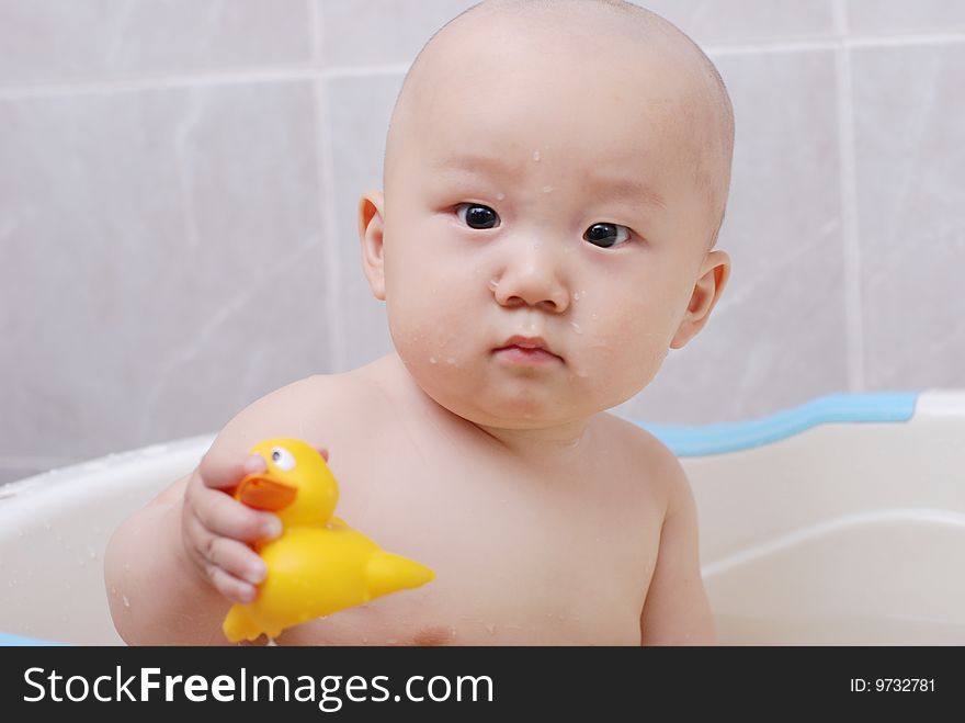 Asian baby boy holding  a yellow plastic duck in bath. Asian baby boy holding  a yellow plastic duck in bath